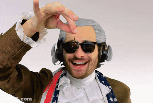 A Man Wearing A Wig And Headphones Is Holding A Cherry In His Hand GIF