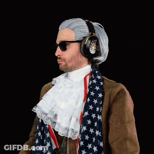 A Man Wearing A Wig And Headphones Is Wearing An American Flag Scarf Around His Neck GIF