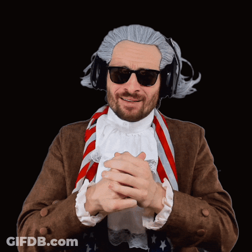 A Man Wearing A Wig And Sunglasses Has His Hands Folded In Front Of Him GIF