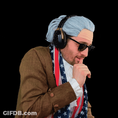 A Man Wearing A Wig And Sunglasses Holds An American Flag Around His Neck GIF
