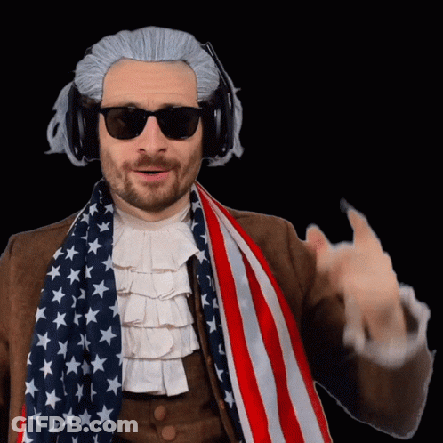 A Man Wearing A Wig And Sunglasses Holds An American Flag Around His Neck GIF