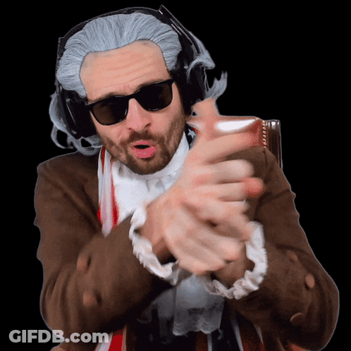A Man Wearing A Wig And Sunglasses Is Making A Gesture With His Hands GIF