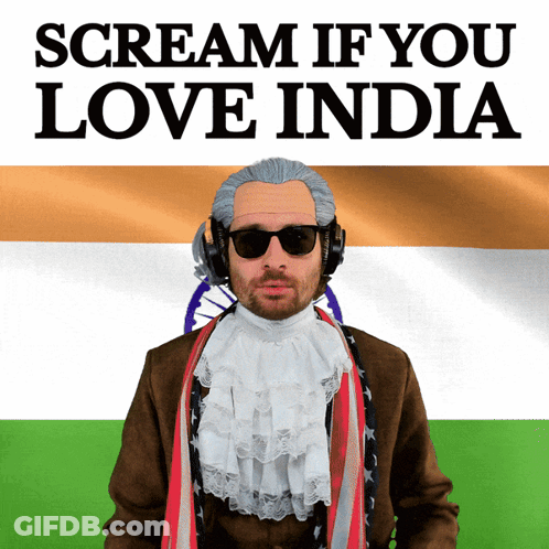 A Man Wearing A Wig And Sunglasses Stands In Front Of A Flag And A Sign That Says Scream If You Love India GIF