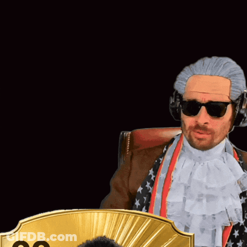 A Man Wearing A Wig And Sunglasses Stands Next To A Man Wearing A Suit And Tie With The Number 99 On It GIF