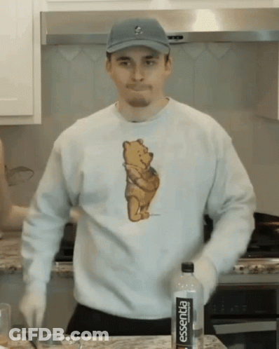 A Man Wearing A Winnie The Pooh Shirt Is Standing In Front Of A Bottle Of Essentia GIF