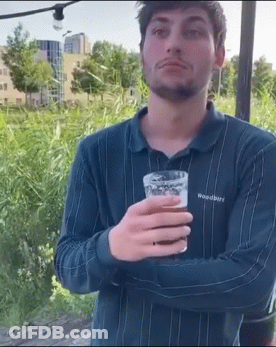 A Man Wearing A Woodbird Shirt Is Holding A Glass Of Beer . GIF