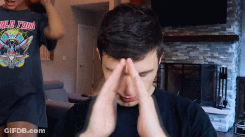 A Man Wearing A World Tour T-Shirt Is Covering His Face With His Hands GIF