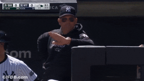 A Man Wearing A Yankees Sweatshirt Is Standing In Front Of A Scoreboard GIF