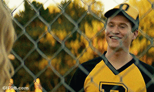 A Man Wearing A Yellow And Black Jersey With The Letter P On It Is Smiling Behind A Chain Link Fence . GIF