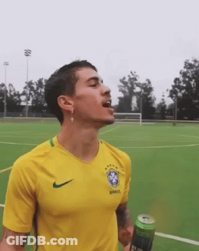A Man Wearing A Yellow Brasil Shirt Is Drinking From A Green Can GIF