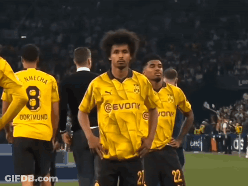 A Man Wearing A Yellow Evonk Jersey Stands In Front Of A Crowd GIF