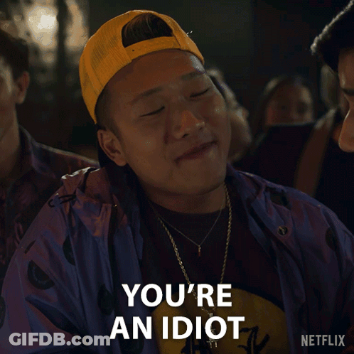 A Man Wearing A Yellow Hat And A Purple Jacket Says " You 'Re An Idiot " GIF