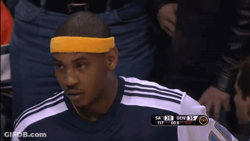 A Man Wearing A Yellow Headband Sits In The Stands During A Basketball Game GIF