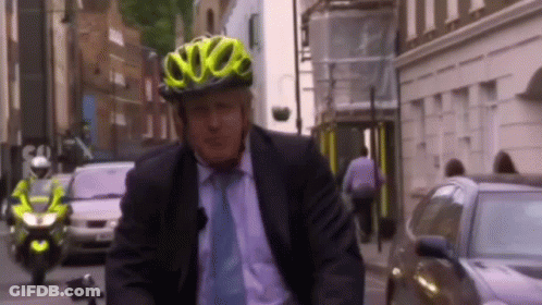 A Man Wearing A Yellow Helmet Is Riding A Bike GIF