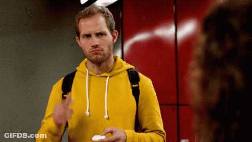 A Man Wearing A Yellow Hoodie Is Holding A White Object GIF