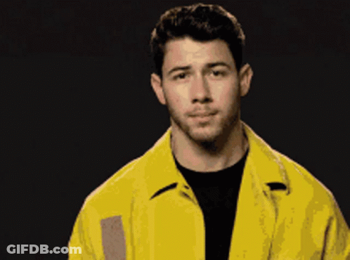 A Man Wearing A Yellow Jacket And A Black Shirt Looks At The Camera GIF