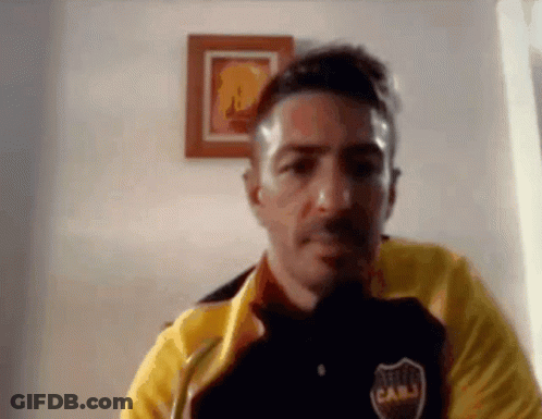 A Man Wearing A Yellow Jacket And A Black Shirt With The Word Cabj On It Is Looking At The Camera . GIF