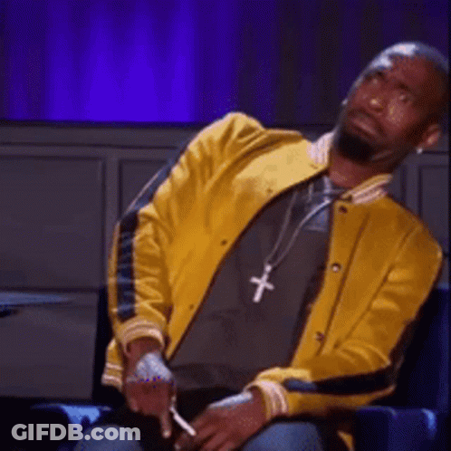 A Man Wearing A Yellow Jacket And A Necklace With A Cross On It GIF
