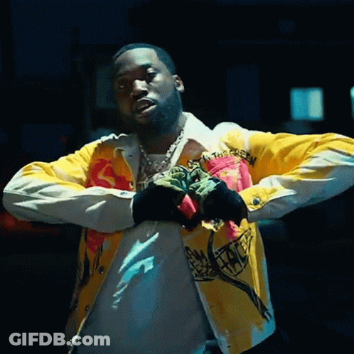 A Man Wearing A Yellow Jacket And Black Gloves Is Standing With His Arms Crossed . GIF