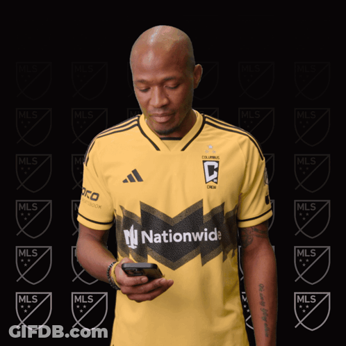 A Man Wearing A Yellow Jersey That Says Nationwide Looks At His Phone GIF