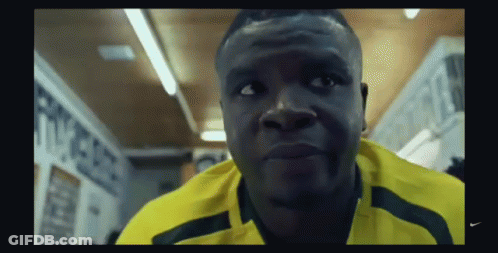 A Man Wearing A Yellow Nike Shirt Is Looking At The Camera GIF