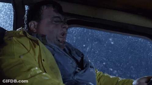 A Man Wearing A Yellow Raincoat Is Driving A Car In The Rain GIF
