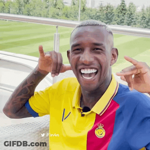 A Man Wearing A Yellow Red And Blue Shirt With A Crown On The Front GIF