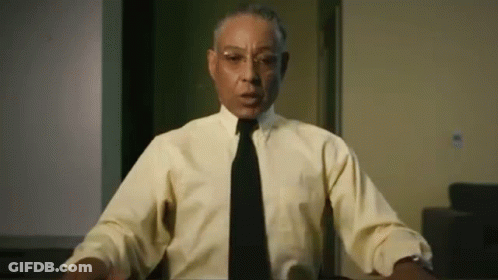 A Man Wearing A Yellow Shirt And A Black Tie Is Sitting At A Table . GIF