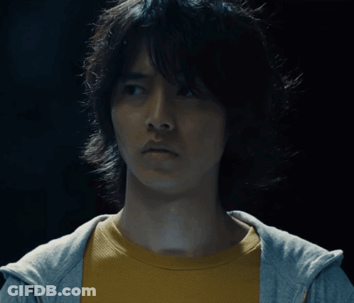 A Man Wearing A Yellow Shirt And A Gray Hoodie Looks At The Camera GIF
