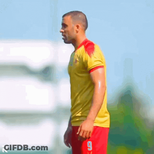 A Man Wearing A Yellow Shirt And Red Shorts With The Number 9 On The Shorts GIF