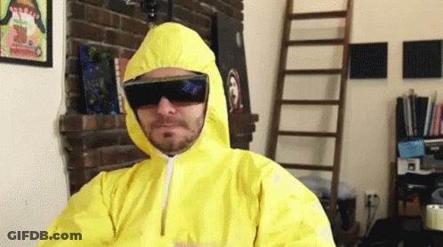 A Man Wearing A Yellow Suit And Sunglasses Is Standing In Front Of A Fireplace GIF