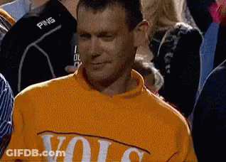 A Man Wearing A Yellow Sweater With The Word Volc On It Is Standing In A Crowd Of People . GIF