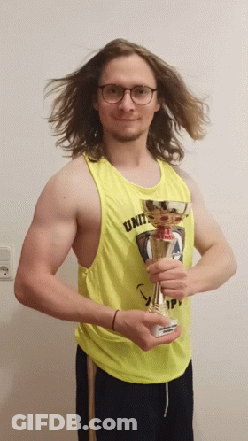 A Man Wearing A Yellow Tank Top That Says Unit Holds A Trophy GIF