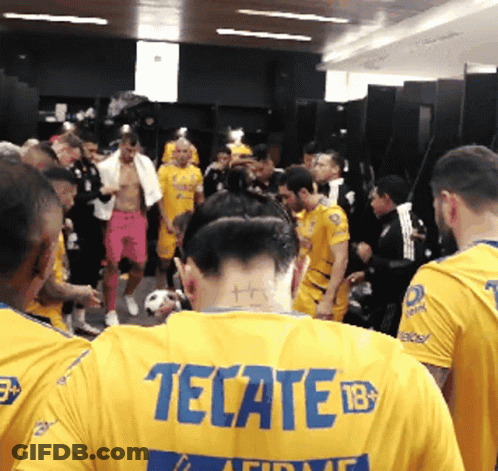 A Man Wearing A Yellow Tecate Jersey Is Surrounded By Other Men GIF