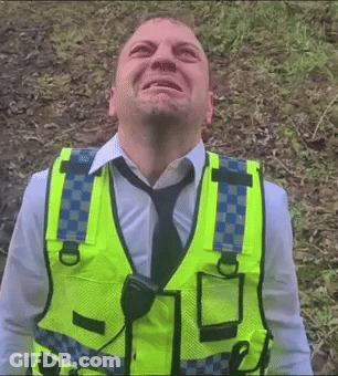 A Man Wearing A Yellow Vest And Tie Looks Up At Something GIF