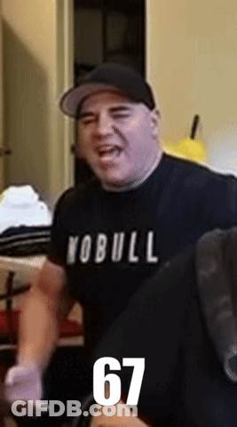 A Man Wearing A Yobull Shirt And A Hat Is Standing In A Room GIF