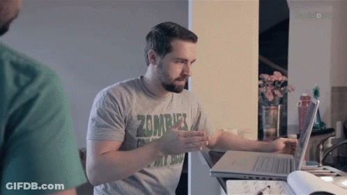 A Man Wearing A Zombie T-Shirt Is Using A Laptop Computer GIF