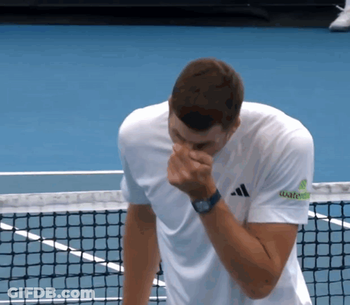 A Man Wearing An Adidas Shirt Wipes His Nose With His Hand GIF