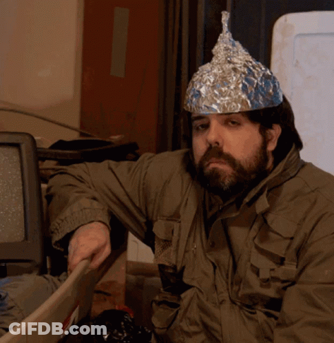 A Man Wearing An Aluminum Foil Hat Is Sitting In Front Of A Computer GIF