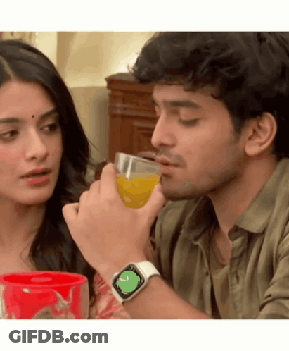 A Man Wearing An Apple Watch Is Drinking Orange Juice Next To A Woman GIF