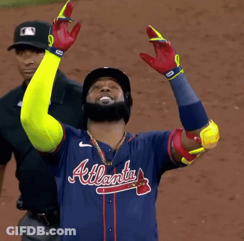 A Man Wearing An Atlanta Baseball Jersey Holds His Arms Up In The Air GIF