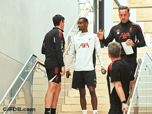 A Man Wearing An Aya Shirt Talks To Another Man On The Stairs GIF