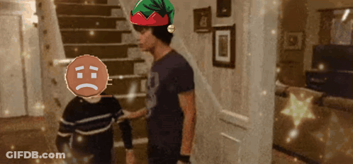 A Man Wearing An Elf Hat Is Talking To A Boy With A Sad Face GIF
