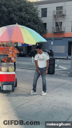 A Man Wearing An Emirates Shirt Is Standing In Front Of A Cart GIF