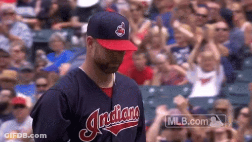 A Man Wearing An Indians Baseball Uniform Stands In Front Of A Crowd GIF