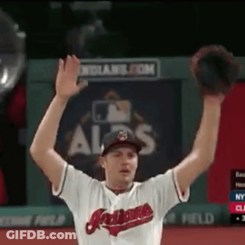 A Man Wearing An Indians Jersey Is Raising His Hands In The Air GIF
