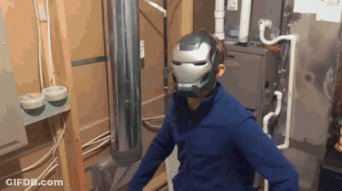 A Man Wearing An Iron Man Helmet Is Standing In A Room GIF