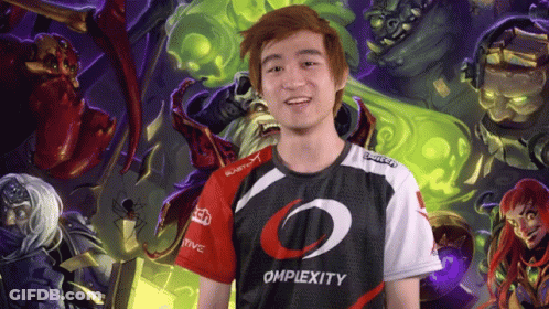 A Man Wearing An Omplexity Shirt Stands In Front Of A Painting GIF