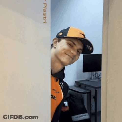 A Man Wearing An Orange And Black Hat Is Peeking Out From Behind A Wall That Says Piastri On It GIF