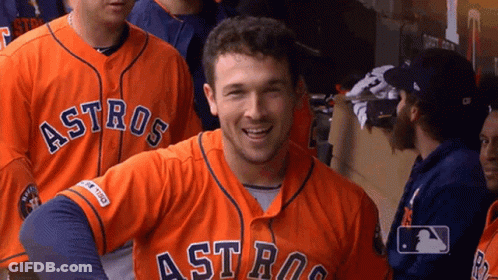 A Man Wearing An Orange Astros Jersey Smiles For The Camera GIF